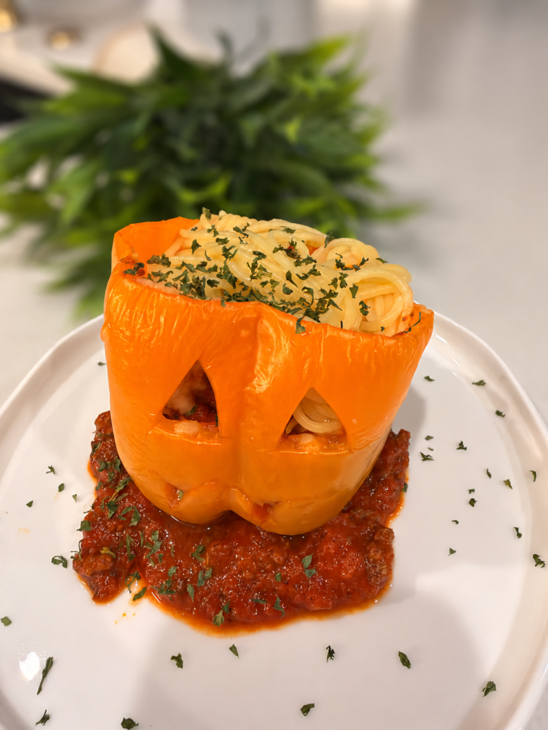 Red, yellow, and orange jack-o&rsquo;-lantern stuffed bell peppers topped with gluten-free spaghetti brains.